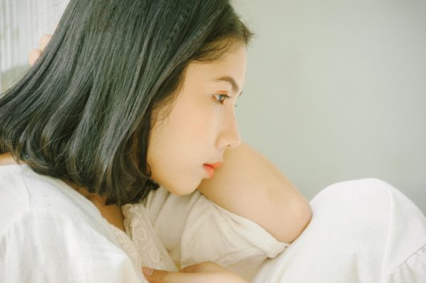 イケない悩み、ベットで一点を見つめる女性の画像