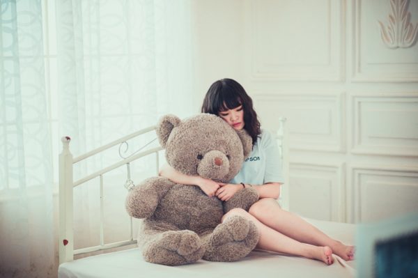就活ブルーで落ち込んでいる女子の画像。ぬいぐるみの熊に癒やされてる画像。