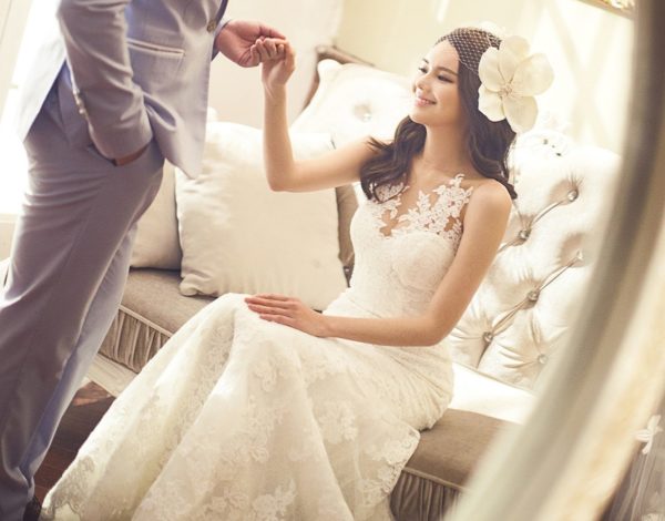 花嫁がソファから立ち上がるのを支える花婿、結婚式の直前の画像