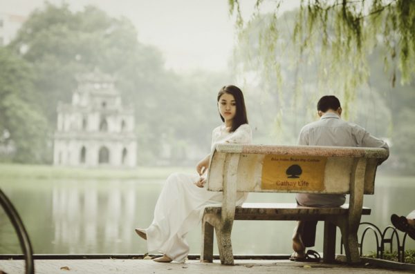 セックスレスのカップルは多く、女性が悩みを抱え込みがちです。画像は公園のベンチに座るカップル。二人の間の心の距離を感じさせます。